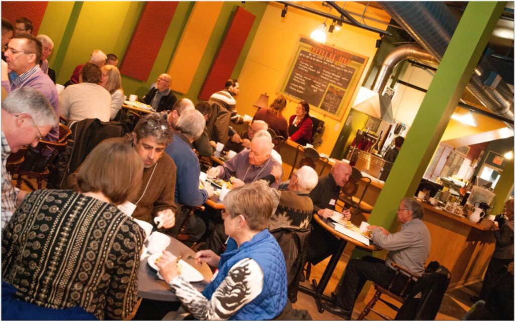 People sit at tables eating and talking inside the colourful Queen Street Commons Cafe space.